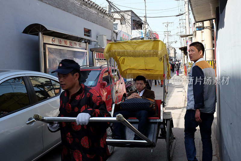 北京胡同里，一个三轮车夫载着游客