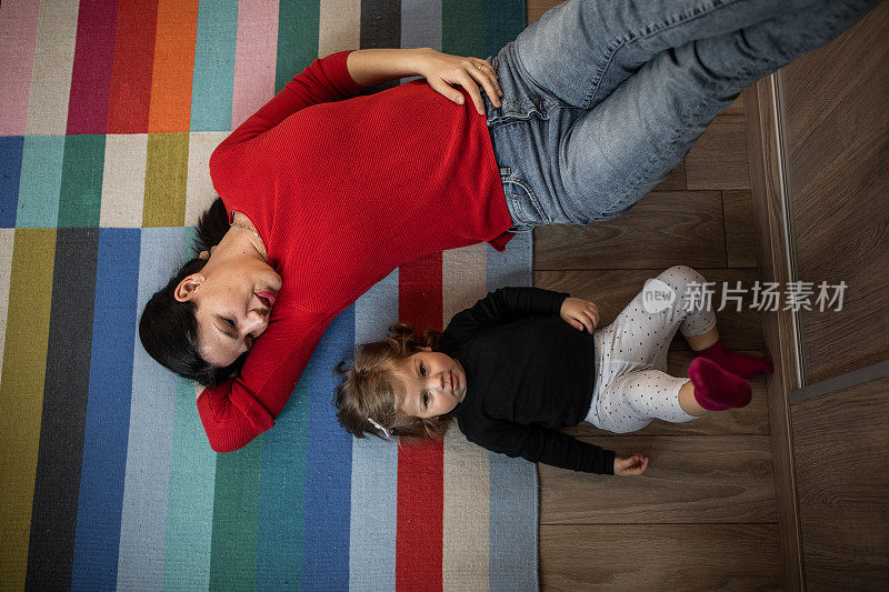 年轻的母亲和女儿躺在地板上