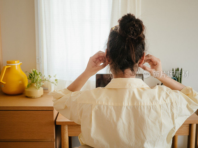 一位亚洲女性在家里开电话会议时使用笔记本电脑。