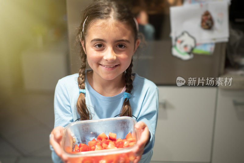 孩子在家做饭。帮助母亲。微笑的小女孩正在准备草莓沙拉