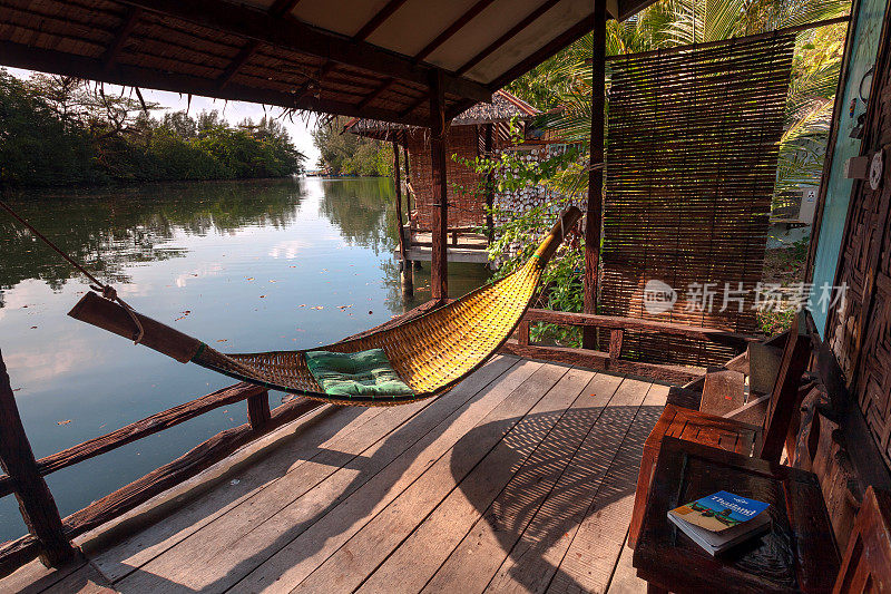河边的竹屋，有吊床，木制露台和东南亚旅游指南