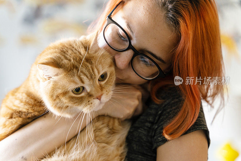 少女抱着她的猫，温柔地抚摸着