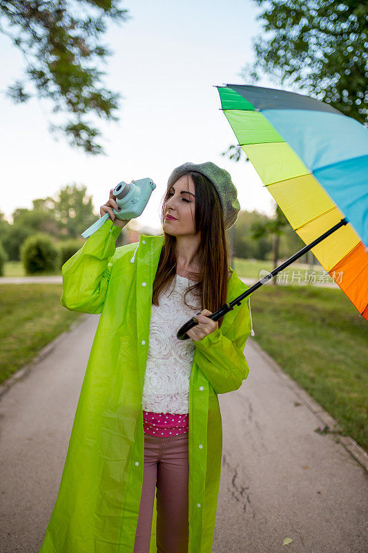 漂亮凉爽的女人带着五颜六色的雨伞在秋天的一天