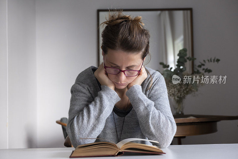 戴眼镜的女人在窗前看书