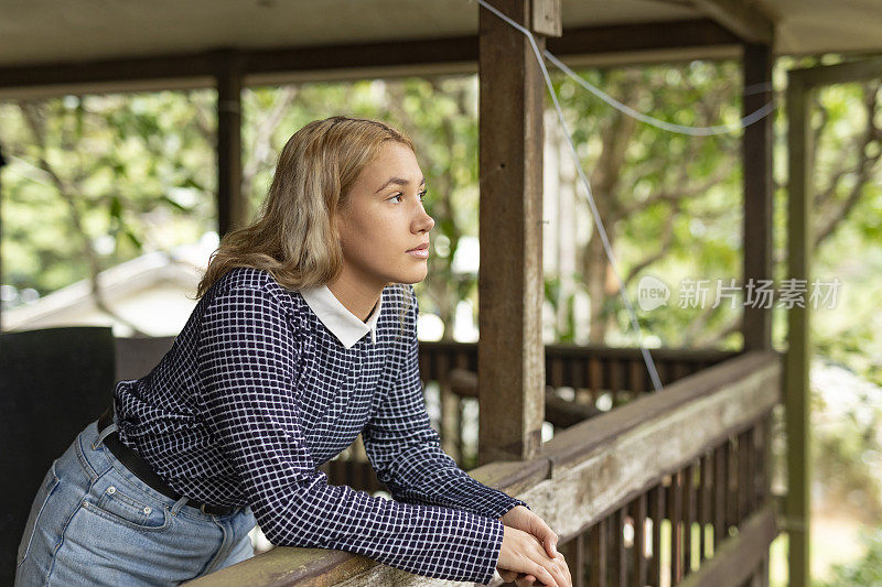 一个年轻女子从房子的阳台眺望远方