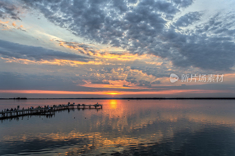 人们的剪影在码头湖边的黄昏与雄伟的云彩景观