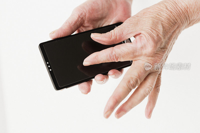 一位老年妇女使用现代智能手机时布满皱纹的双手