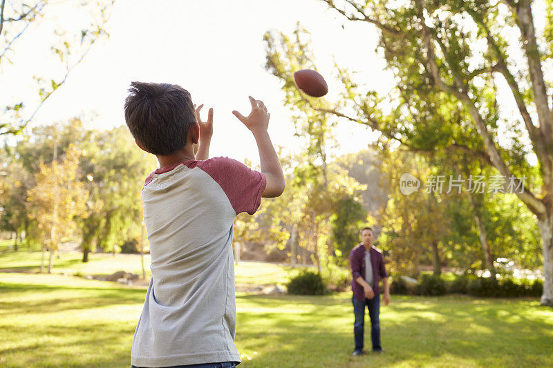 爸爸和儿子互相扔美式足球