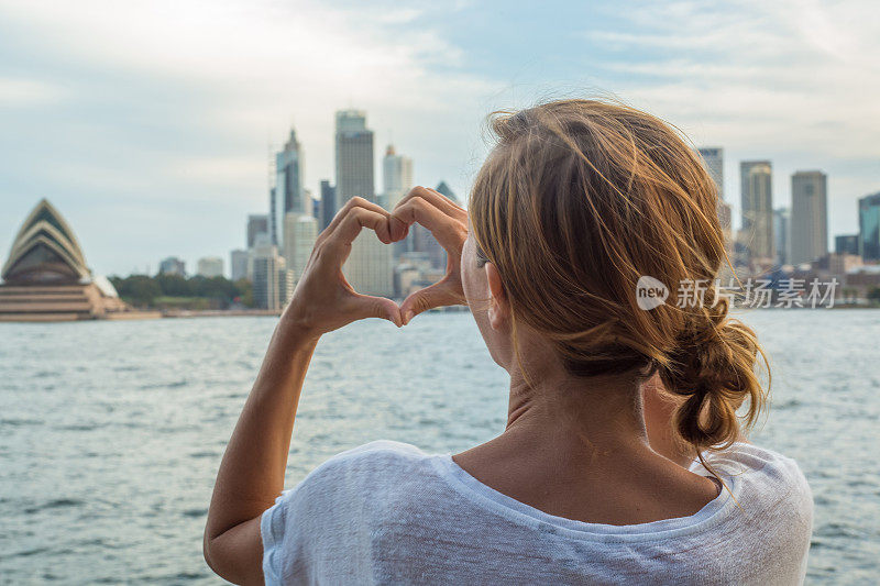 一名女子用心形手指框勾勒出悉尼的天际线