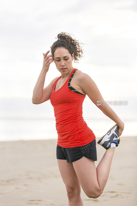 在海滩上伸展的女性跑步者
