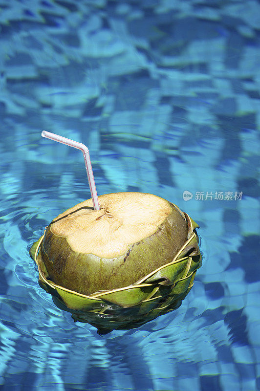 用稻草喝椰子浮在蓝色水池里