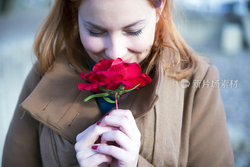 年轻女子闻红玫瑰花的肖像