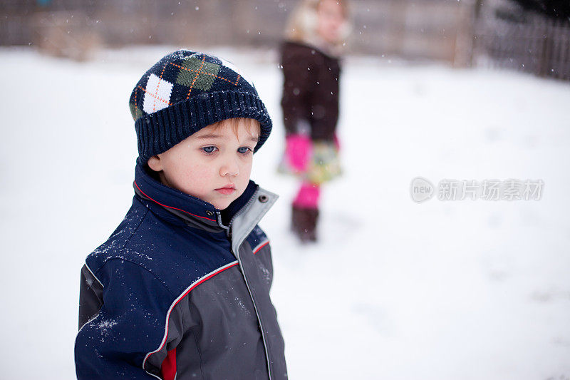 小男孩站在雪地里，一脸的不确定