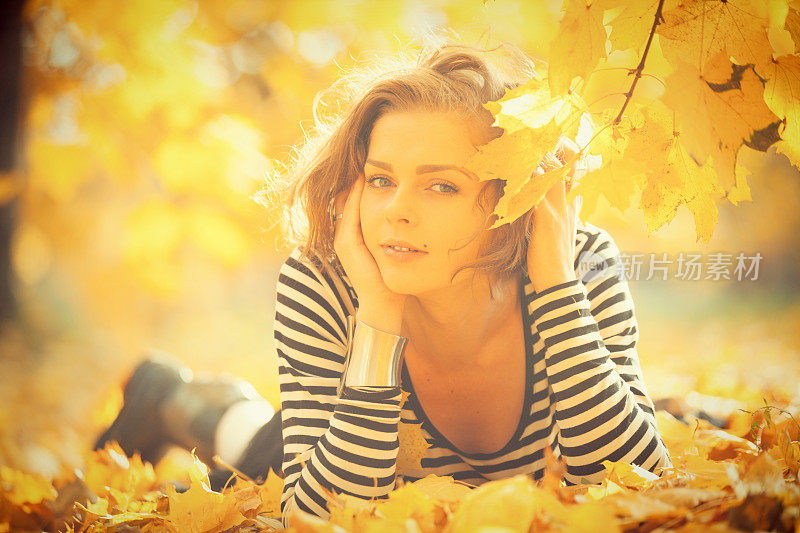 美丽的女人带着秋叶微笑着