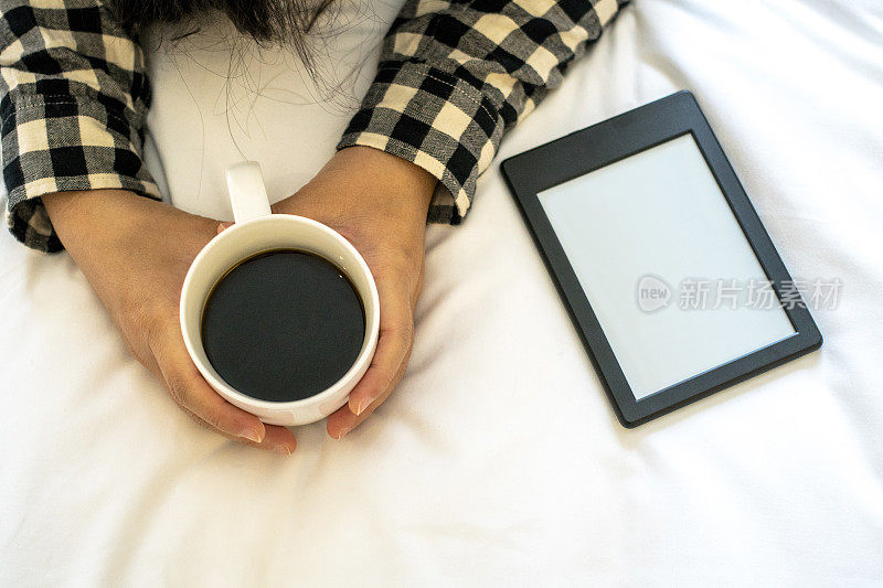 手捧咖啡杯躺在床上，看电子书