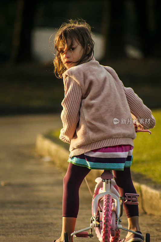 4岁女孩的肖像在她的自行车在日落