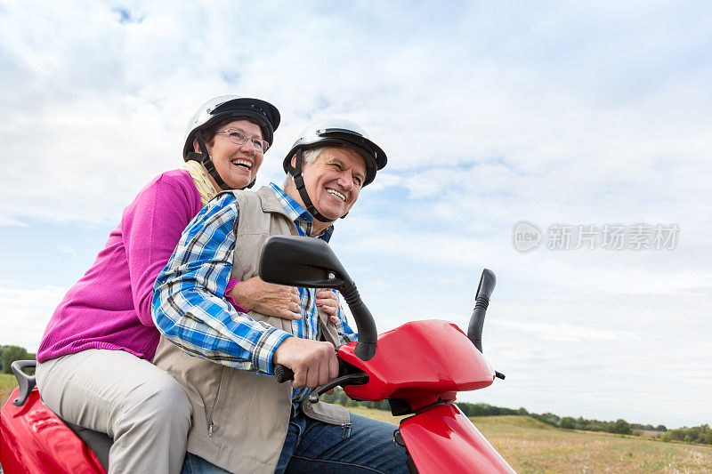 在一个阳光明媚的日子里，一对快乐的老年夫妇骑着摩托车