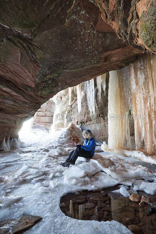 一个女人在冰洞里用手机发短信