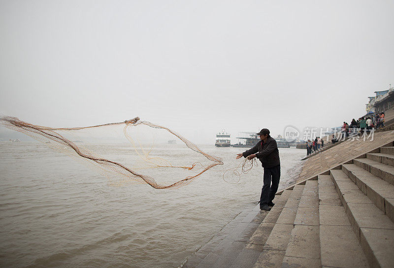 渔民在长江上撒网，身后是商船