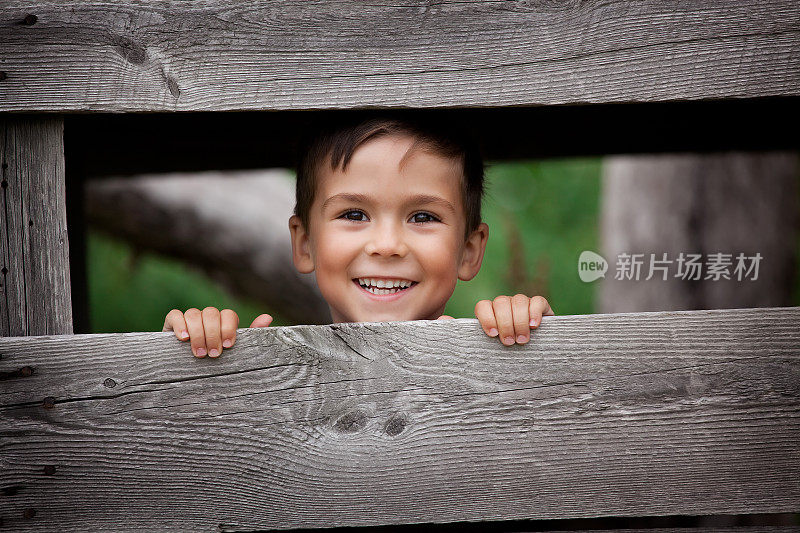 小男孩从棚屋的木板间笑了出来