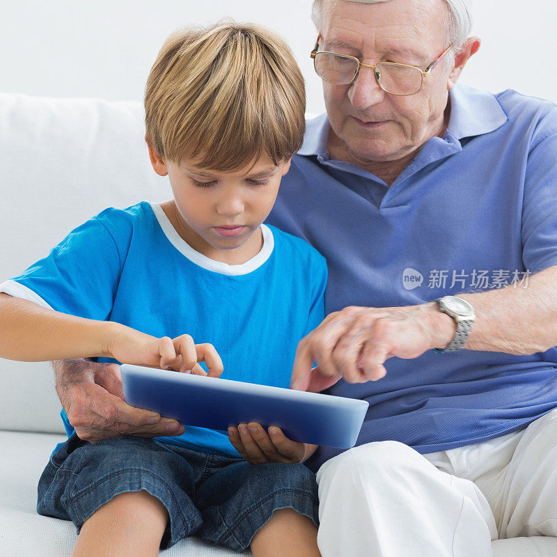 爷爷和他的孙子在用平板电脑