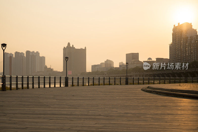 河边的木制平台，夕阳下的城市景观