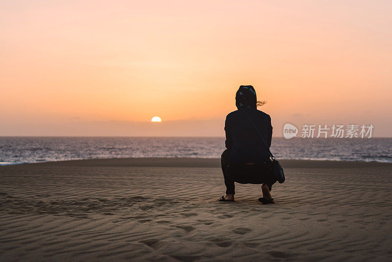 在沙滩上享受日出的女人