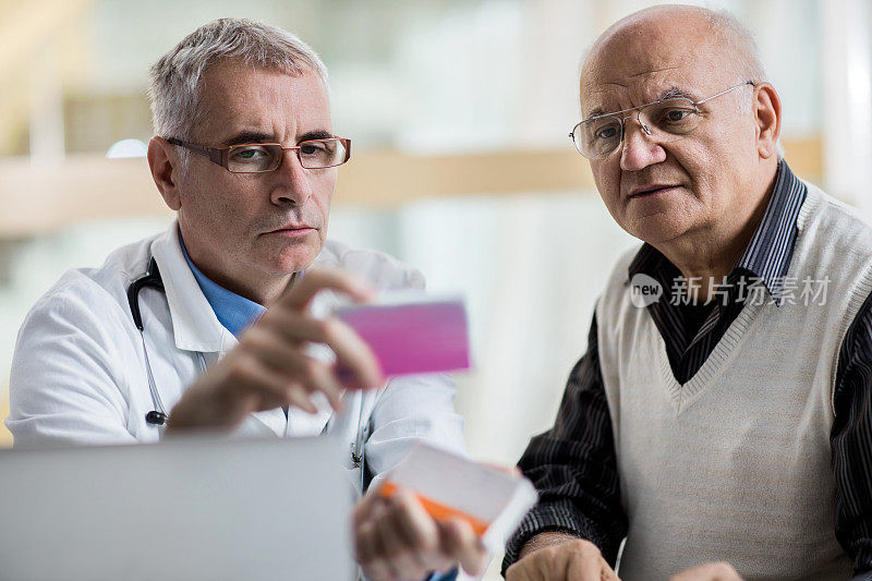 医生和老人在医生的办公室检查处方药物。