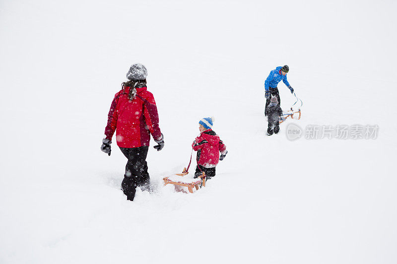 一个年轻的家庭驾着雪橇去旅行