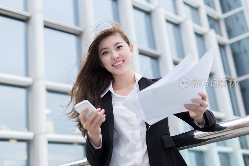 亚洲成功的商业女性使用智能手机分析文件户外