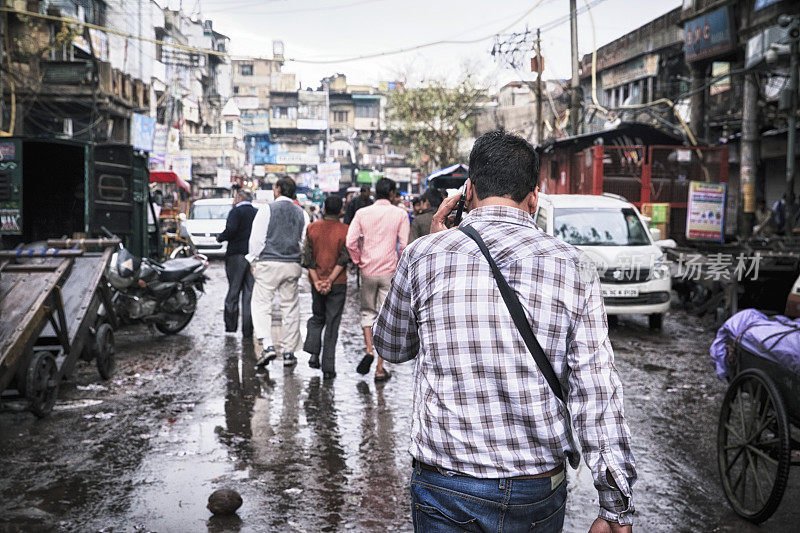 在德里走路的现代人，正在讲电话。