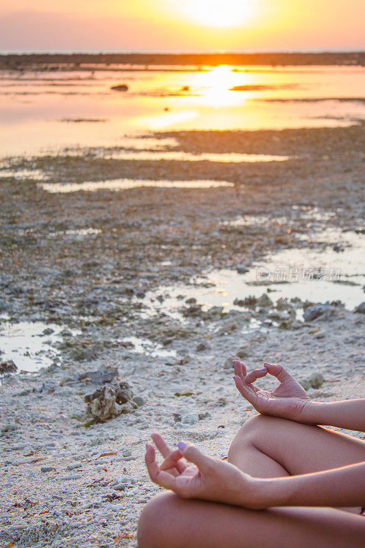 日落时分，在海滩上，一个女人在练习瑜伽