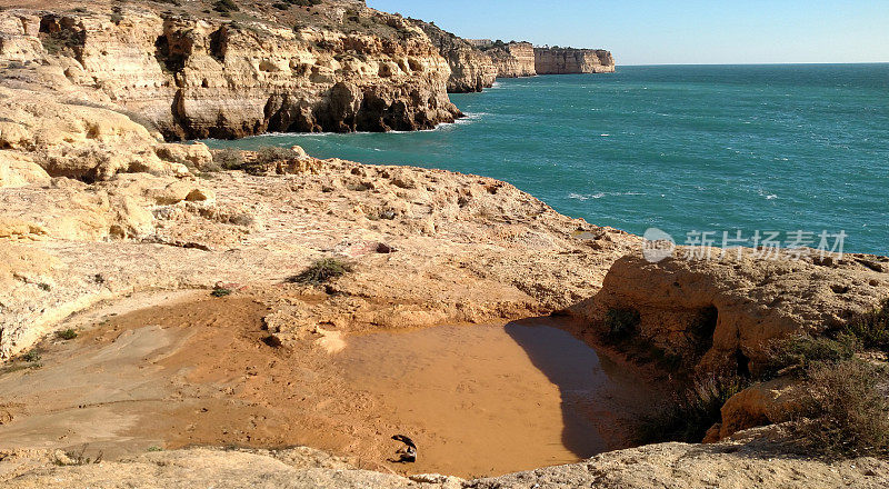 在葡萄牙阿尔加维海岸的石灰岩峭壁上，海面上的浪花聚集了洞穴