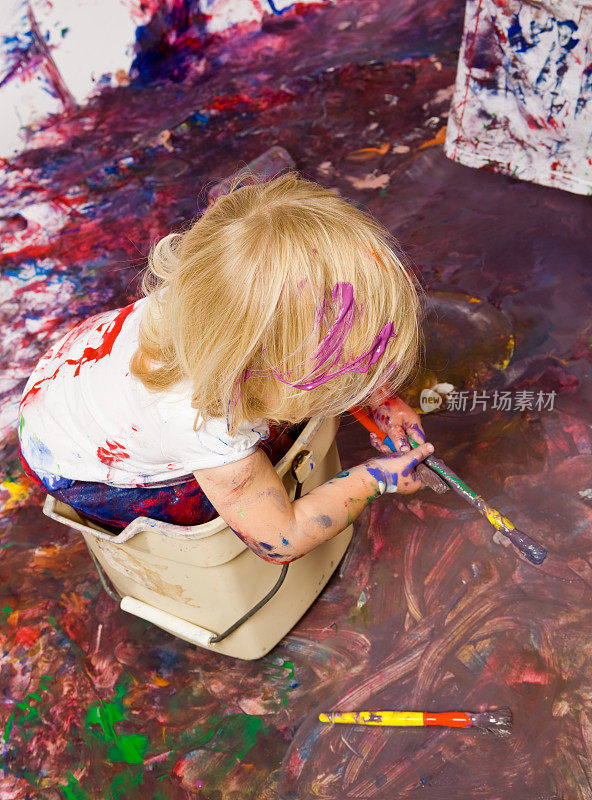 金发的蹒跚学步的女孩在一个桶和两个油漆刷