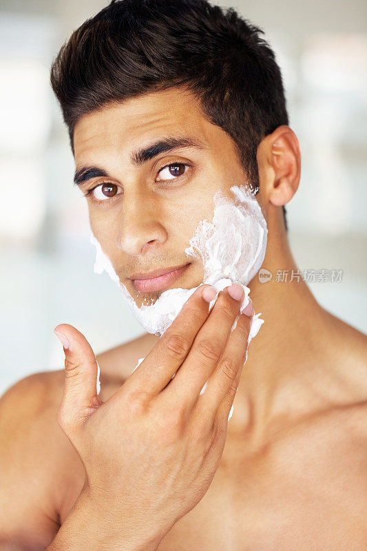 迷人的年轻男子在脸上涂剃须膏
