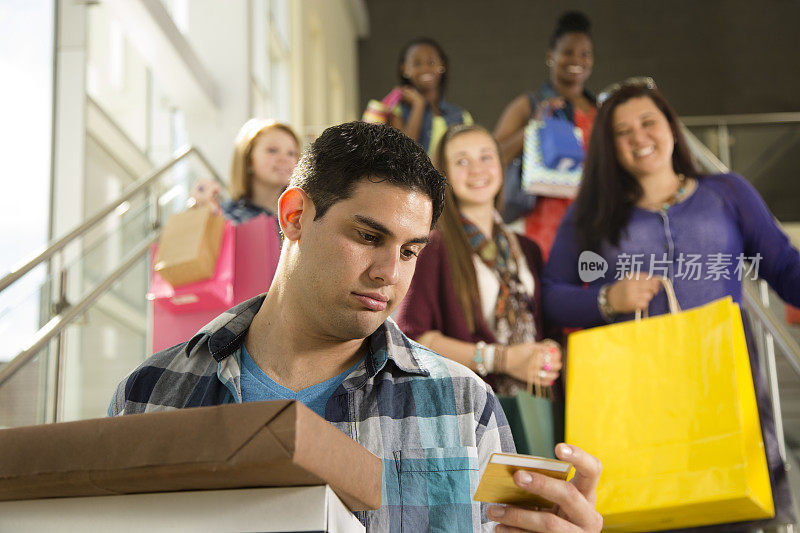 消费主义:购物中心里的购物者。男人持有信用卡。过度消费。