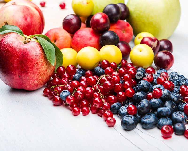 木背景上有蓝莓、红醋栗、浆果、桃子、苹果