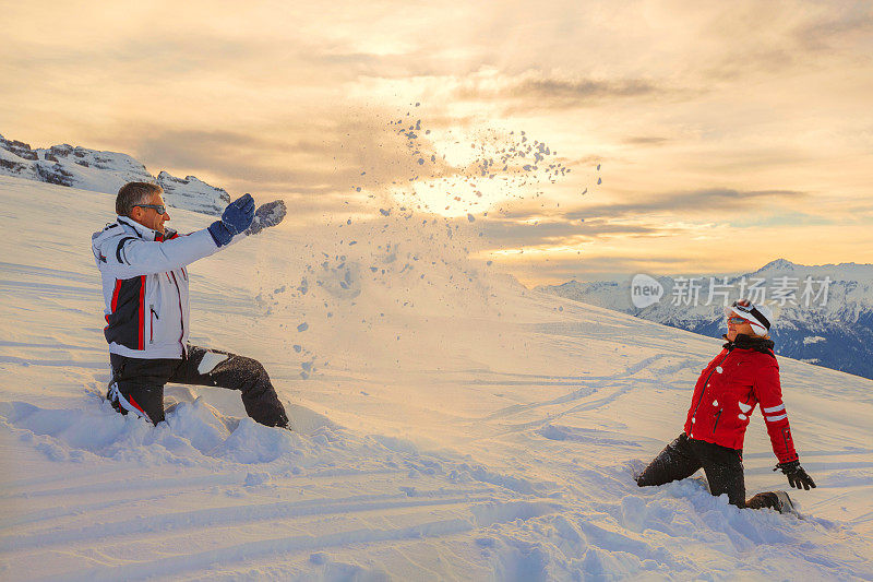 滑雪者夫妇享受玩耍美丽的冬季山脉日落景观