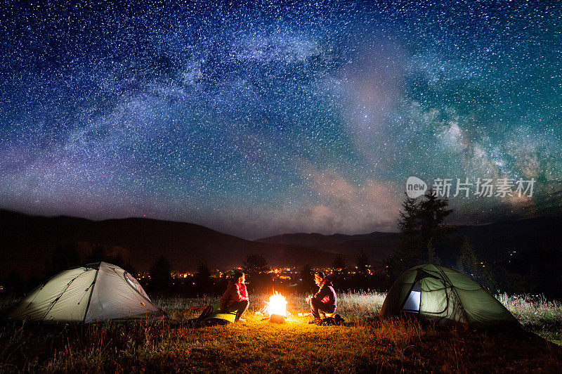 一对浪漫的情侣坐在帐篷附近的篝火旁