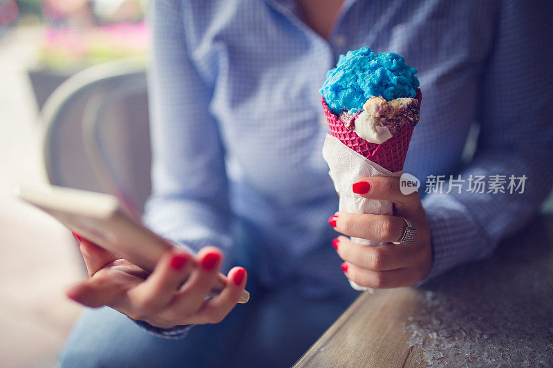 女孩一边吃冰淇淋一边发短信