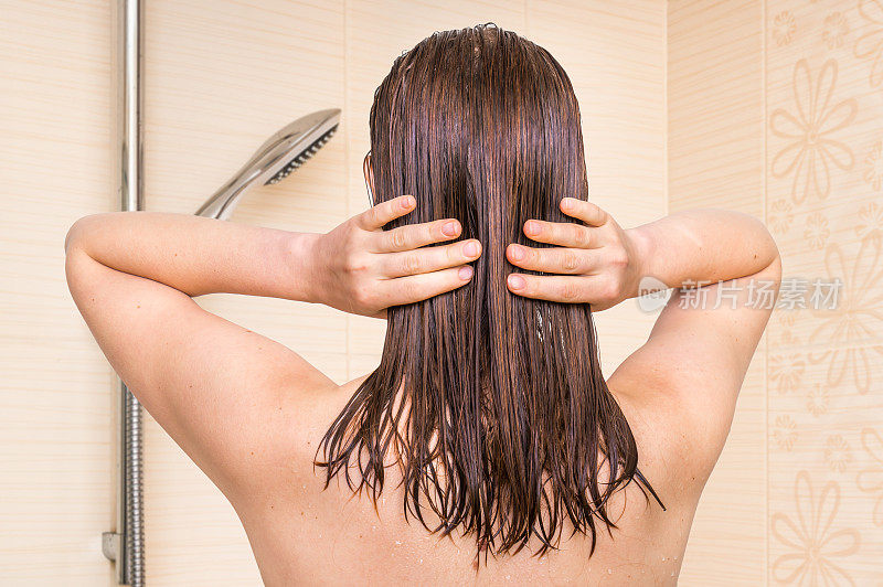 迷人的女人在浴室里给头发涂护发素