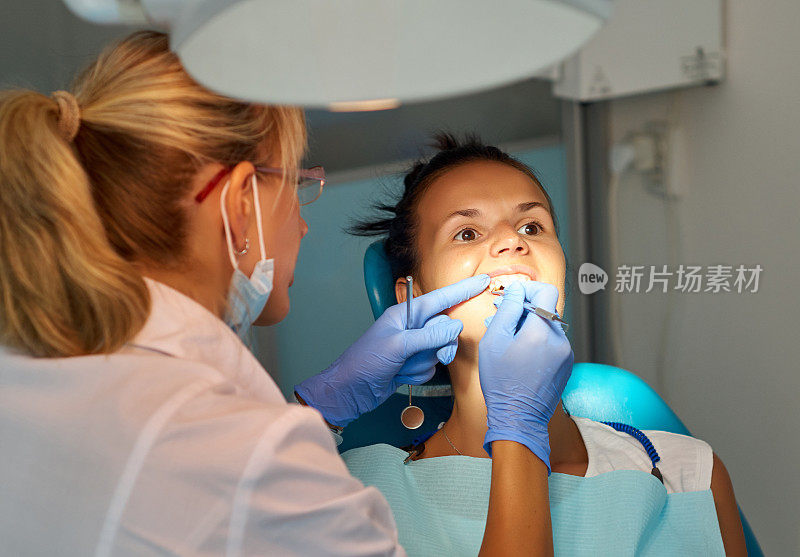 一位美丽的女牙医正在给一个病人治疗牙齿