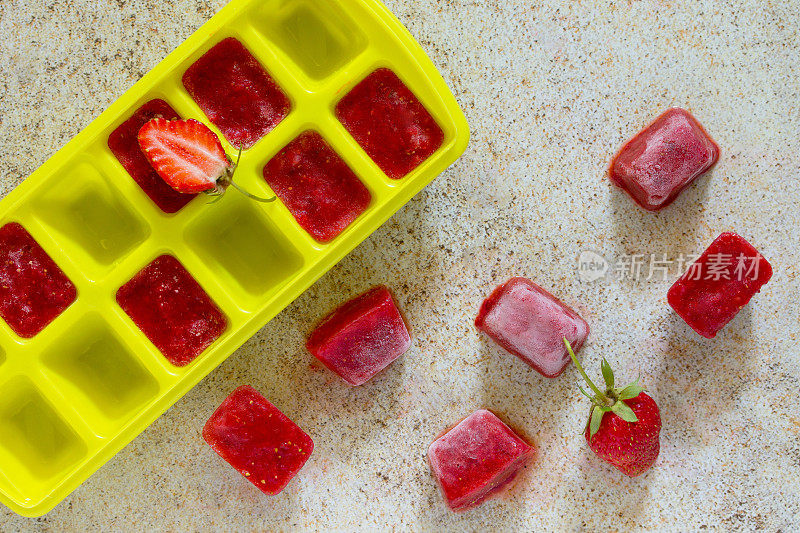 棕色的石头背景上点缀着草莓冰块。用草莓做提神的夏日饮品。