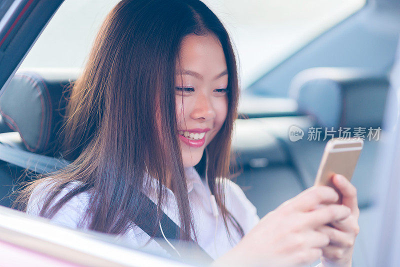 中国年轻女子在车里使用智能手机。