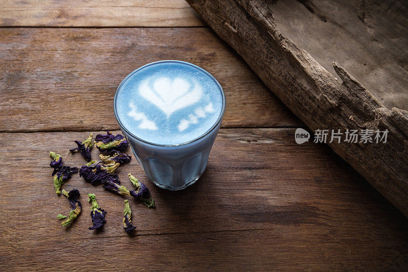 一杯热牛奶蝴蝶豌豆拿铁艺术在咖啡店的木桌上