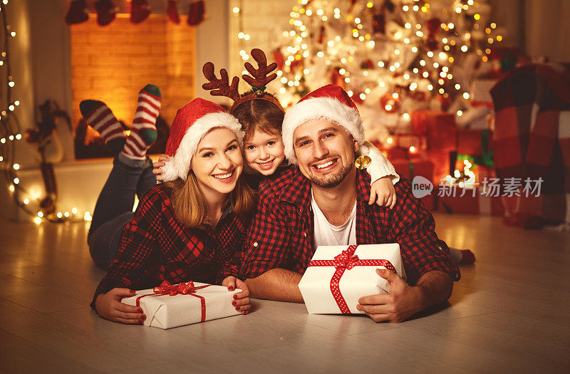 圣诞快乐!幸福的家庭妈妈爸爸和孩子带着神奇的礼物靠近树