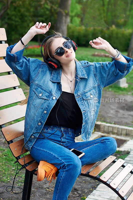 年轻女子戴着耳机在户外用智能手机听音乐