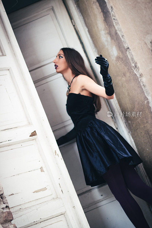 一个穿着黑衣服的女孩站在古老而质朴的门前。