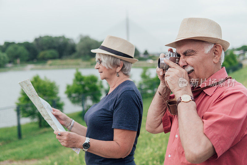 高级游客拍摄自然和他的妻子拿着地图