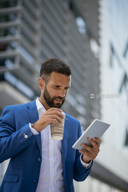 一个商人在喝咖啡休息的时候在平板电脑上工作